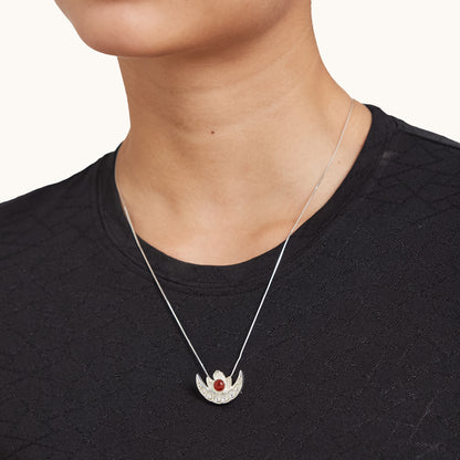 A model wearing a delicate sterling silver half-moon pendant necklace with a red gemstone, styled with a black top.