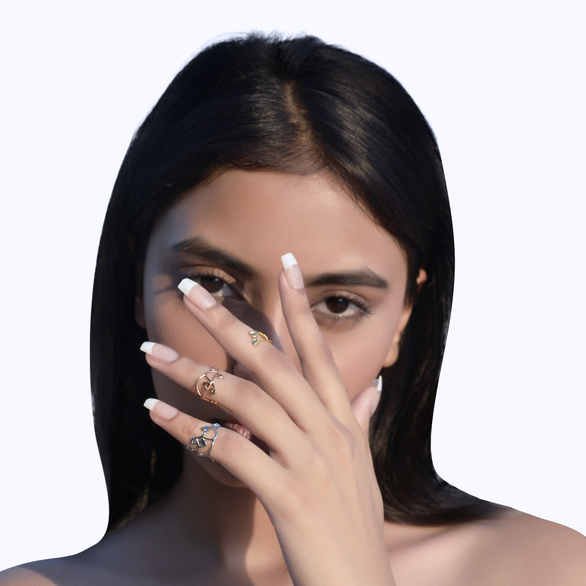 A close-up of a hand wearing multiple delicate, minimalist finger rings in rose gold, yellow gold, and silver, showcasing a trendy stacked-ring aesthetic.