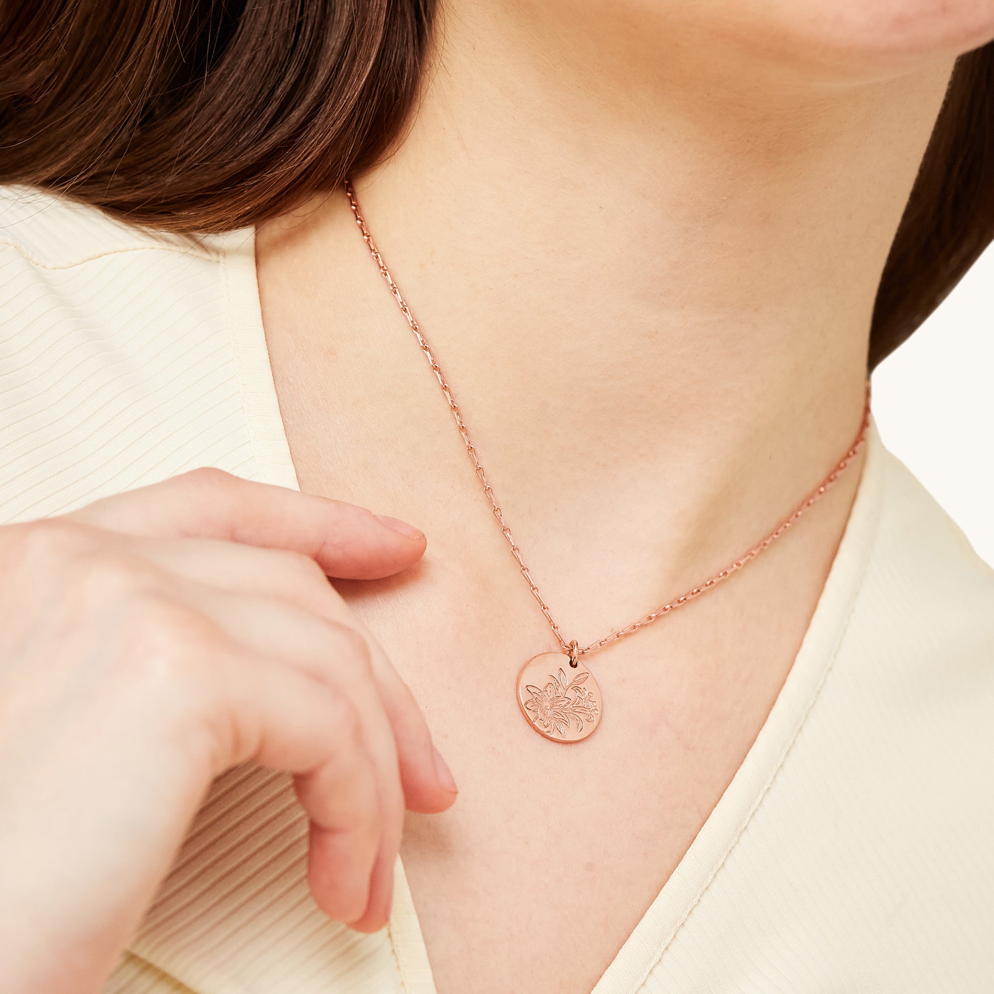 A model wearing a dainty, floral-engraved circular pendant necklace, showcasing its versatile and elegant appeal for everyday styling.