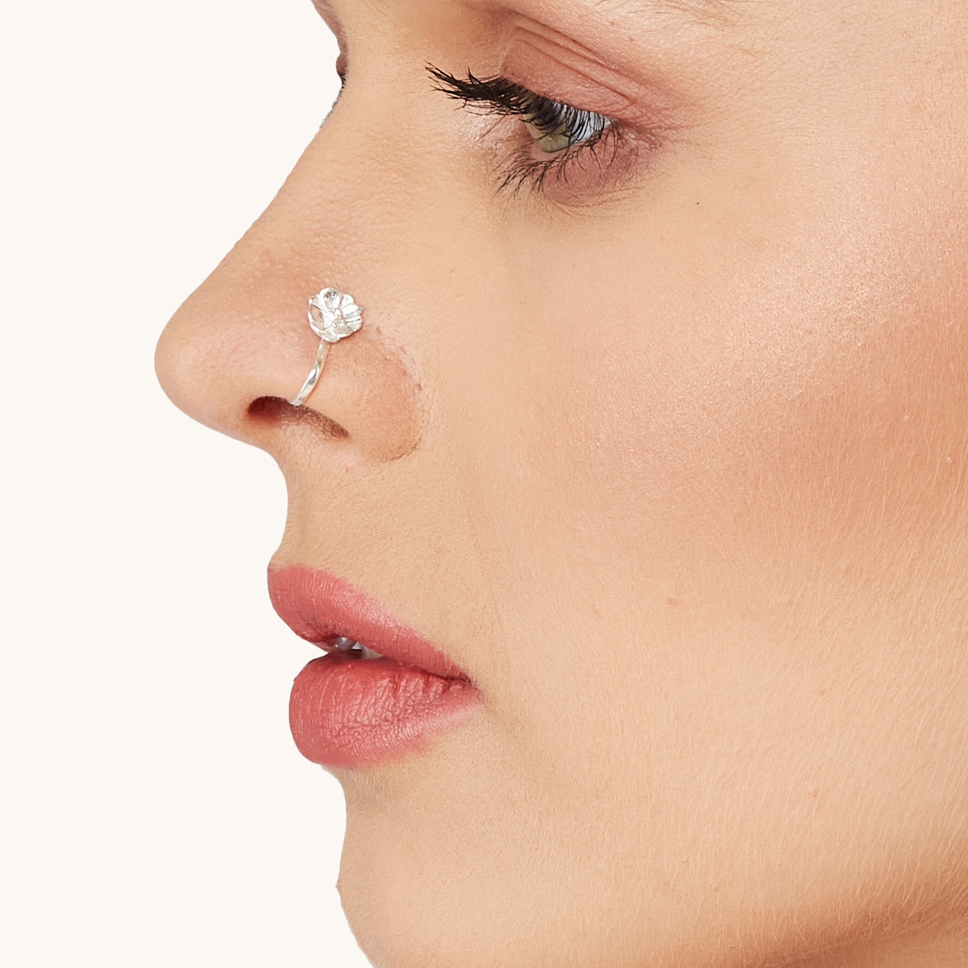 A side-profile studio portrait showcasing a stylish silver botanical-inspired nose clip-on worn by a model, emphasizing the subtle, elegant aesthetic of the accessory.