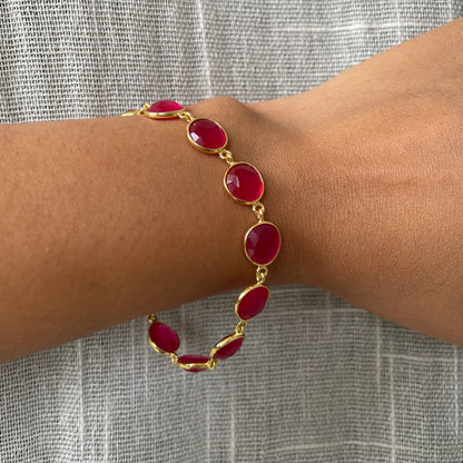 Wrist wearing an adjustable silver chain bracelet with a dainty pink stone in an open bezel setting.