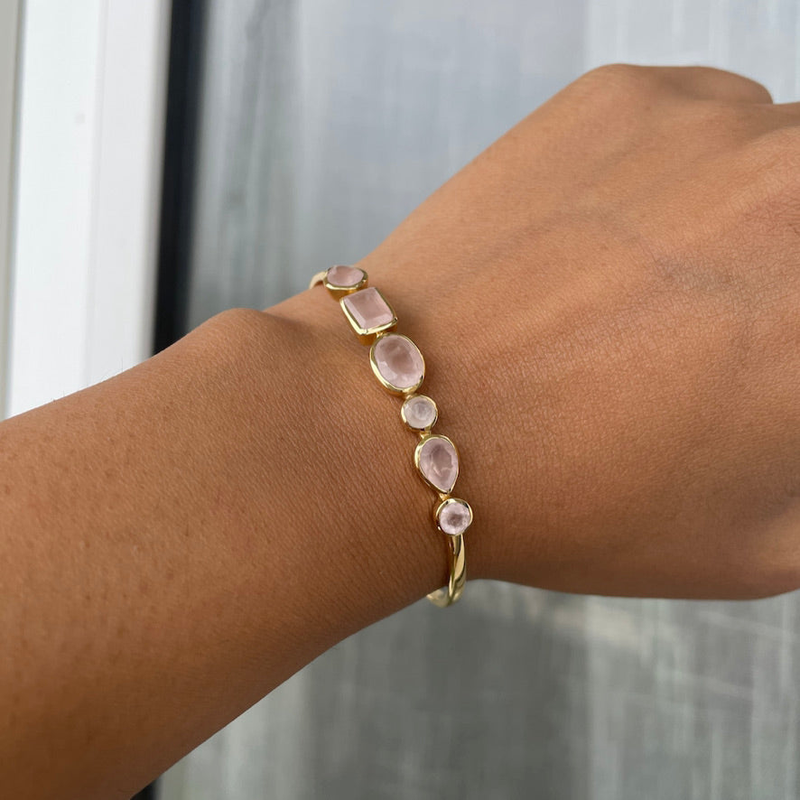 A model wearing a delicate gold cuff bracelet on her wrist adorned with multiple rose quartz gemstones.