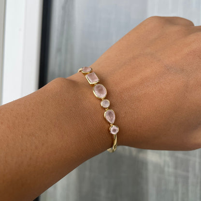 A model wearing a delicate gold cuff bracelet on her wrist adorned with multiple rose quartz gemstones.