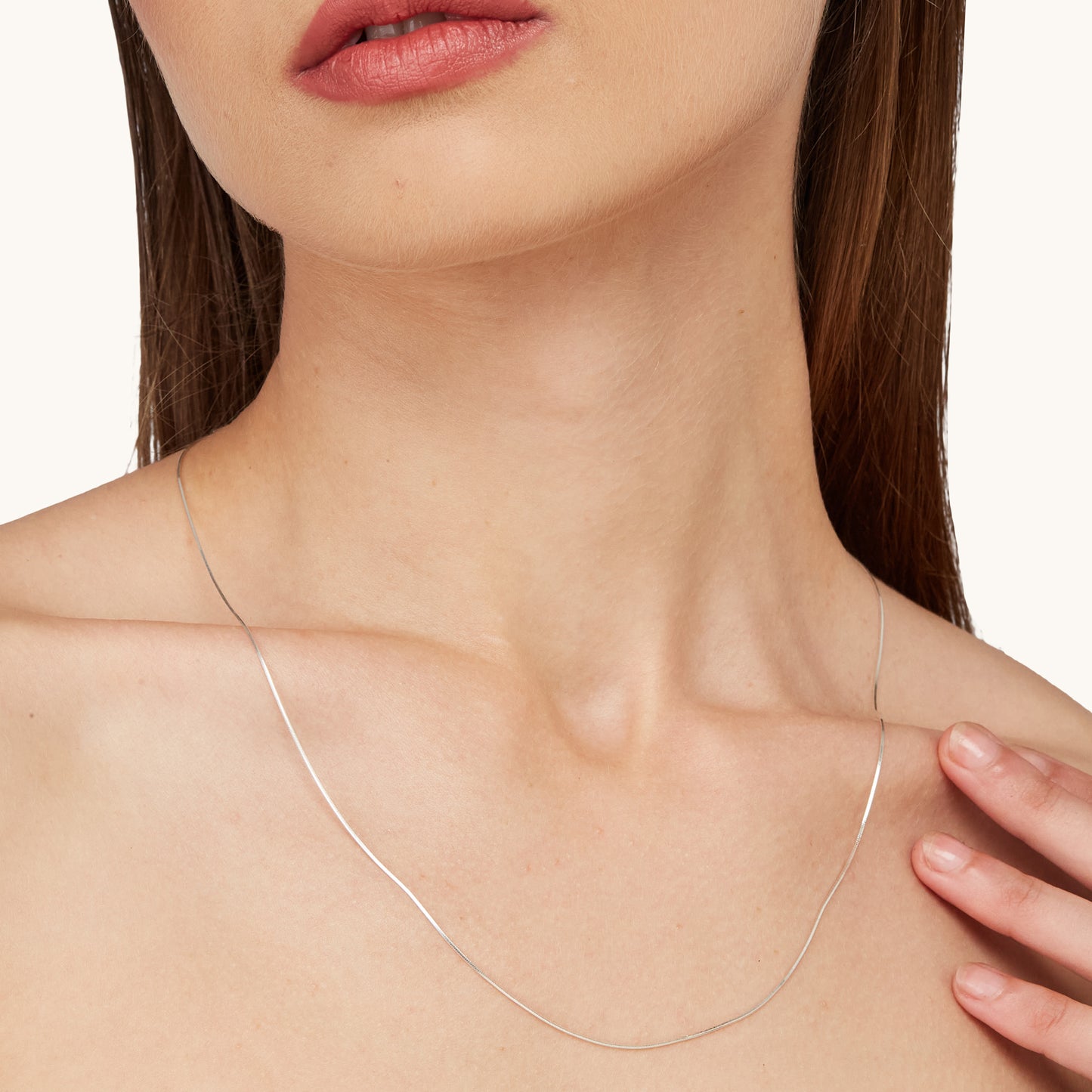 A model wearing a graceful, flowing silver chain necklace that elegantly contours to the collarbone for a modern, minimalist look.