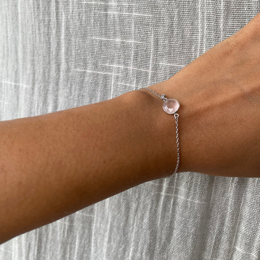 A wrist wearing an elegant, adjustable silver chain bracelet with a subtle pink  stone, styled to showcase its dainty and feminine aesthetic.