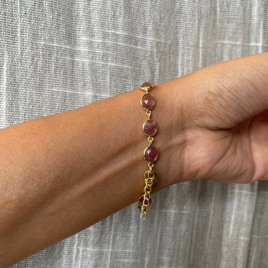 Wrist wearing an elegant, adjustable silver chain bracelet with a delicate speckled pink-red stone.