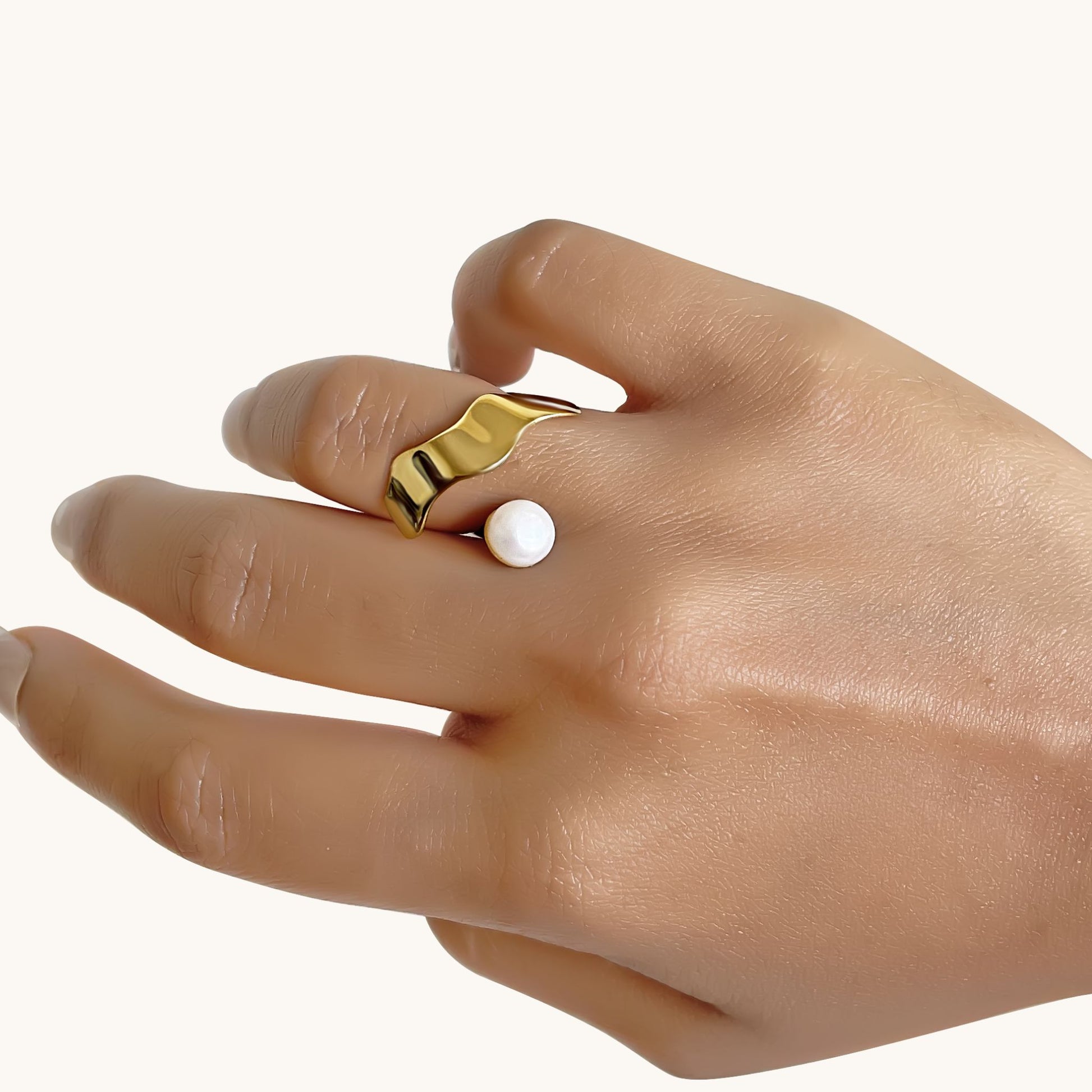 Close-up of a hand wearing an elegant gold-toned, organic-shaped band that follows the natural curve of the finger.