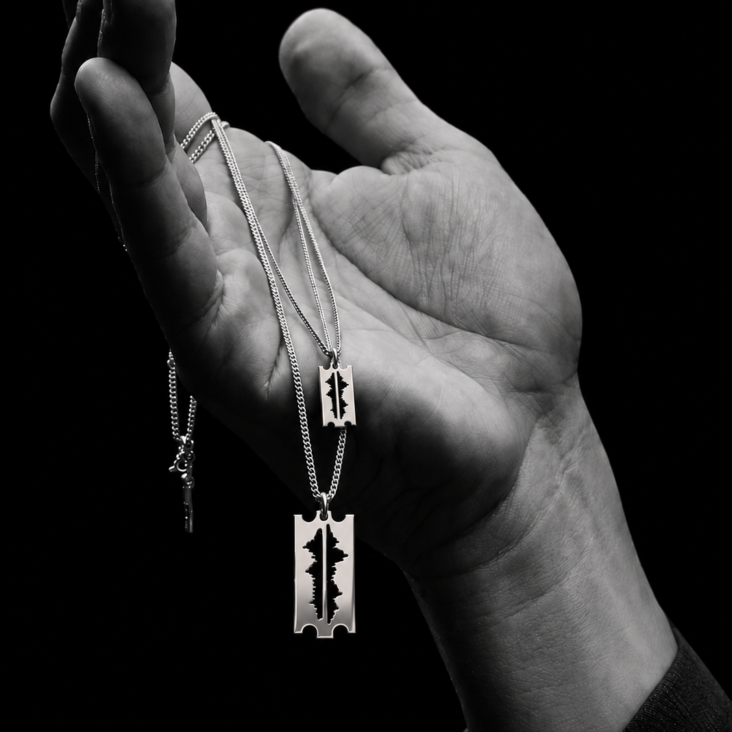 Hand holding the Mountains Are My Lifeline razor-blade pendants in 925 silver, with a mountain-range cut-out, on chains