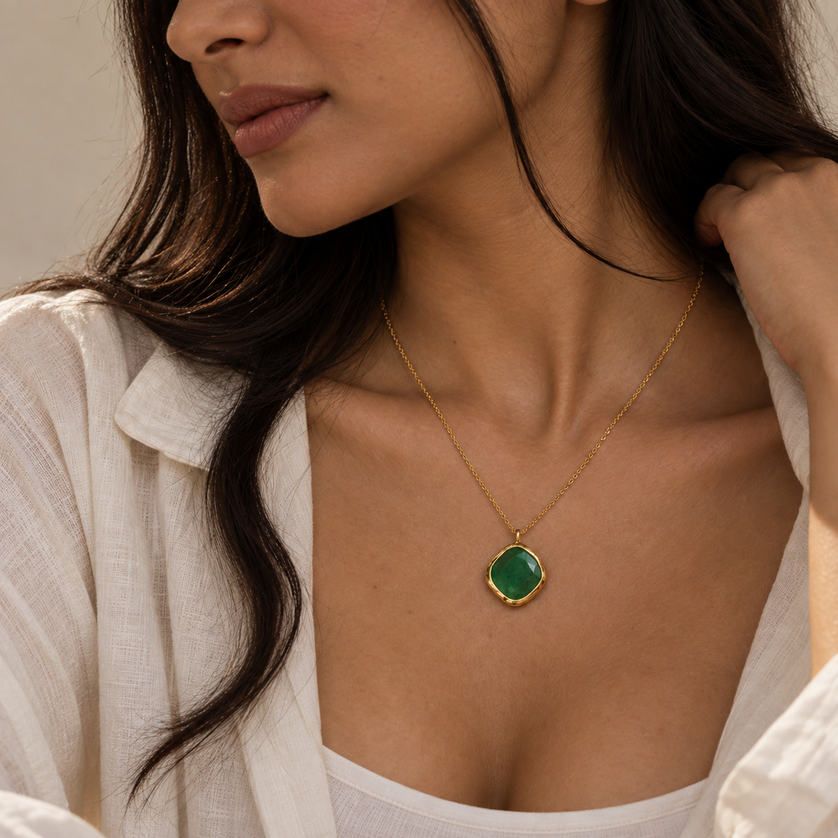 Emerald Glow Pendant featuring an irregular square green onyx stone with an 18kt gold-plated chain, styled on a female model.