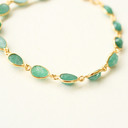 A close-up view showing the bezel-set, oval-cut green beryl stones connected by gold-plated silver links.