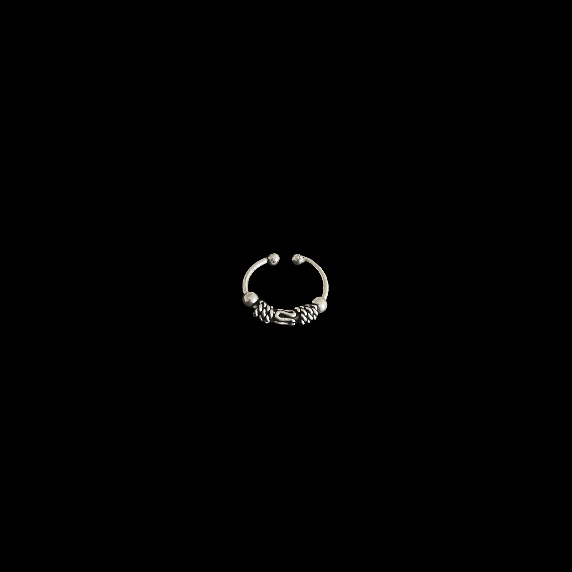 A minimalist view of a circular, oxidised 925 sterling silver piece with intricate metal detailing, isolated on a black background.