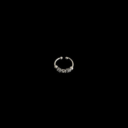 A minimalist view of a circular, oxidised 925 sterling silver piece with intricate metal detailing, isolated on a black background.