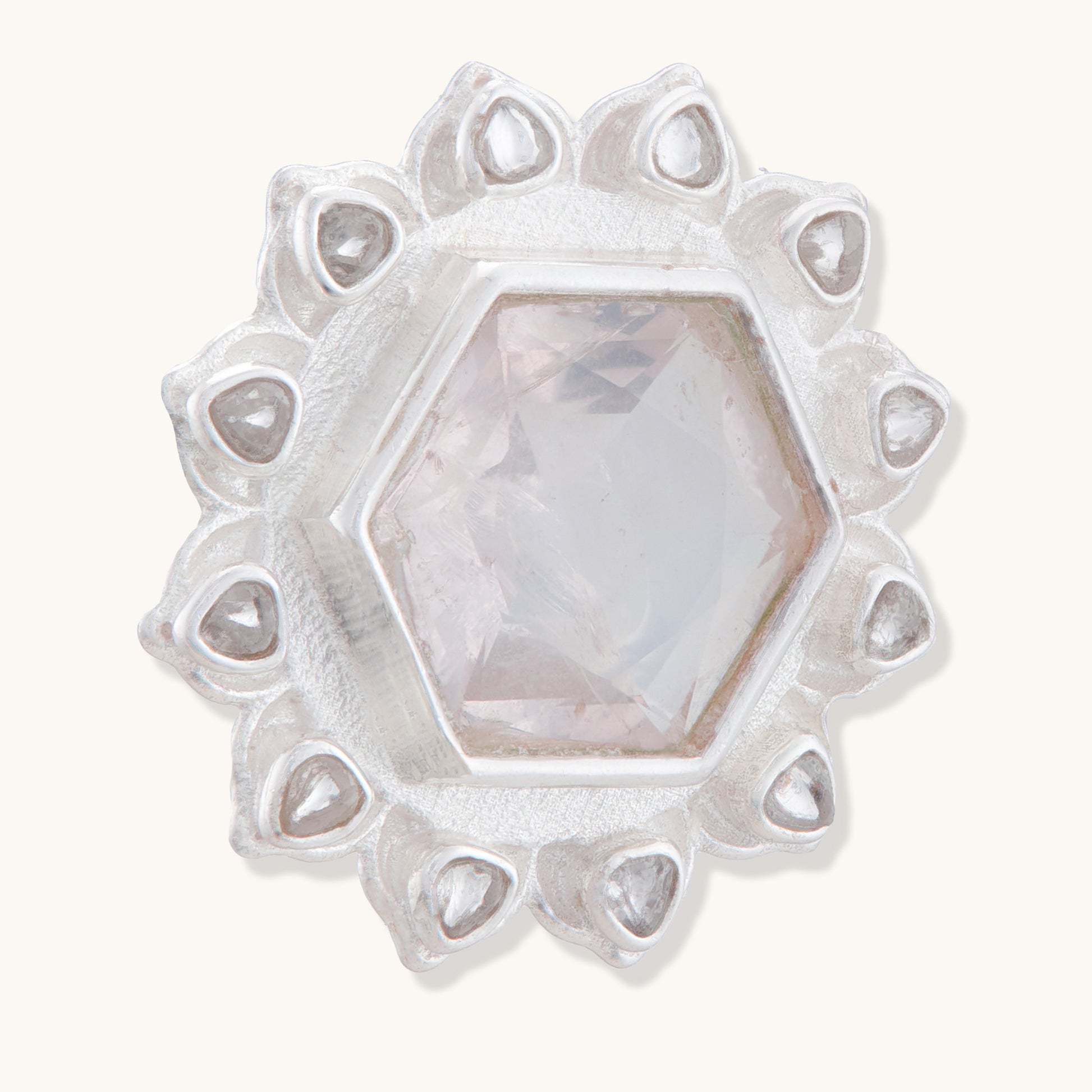 A close-up, angled view of a sterling silver stud earring featuring a pale pink hexagonal gemstone surrounded by a delicate lotus-inspired petal border.