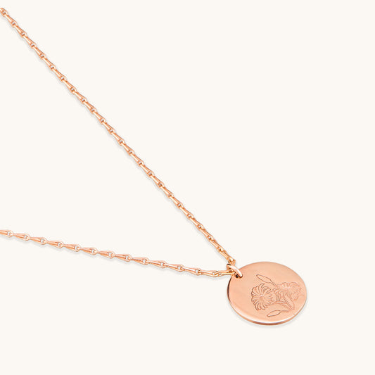 Close-up detail of the Daisy Medallion Necklace showing the intricate botanical engraving on the rose gold disc and the high-quality chain links.
