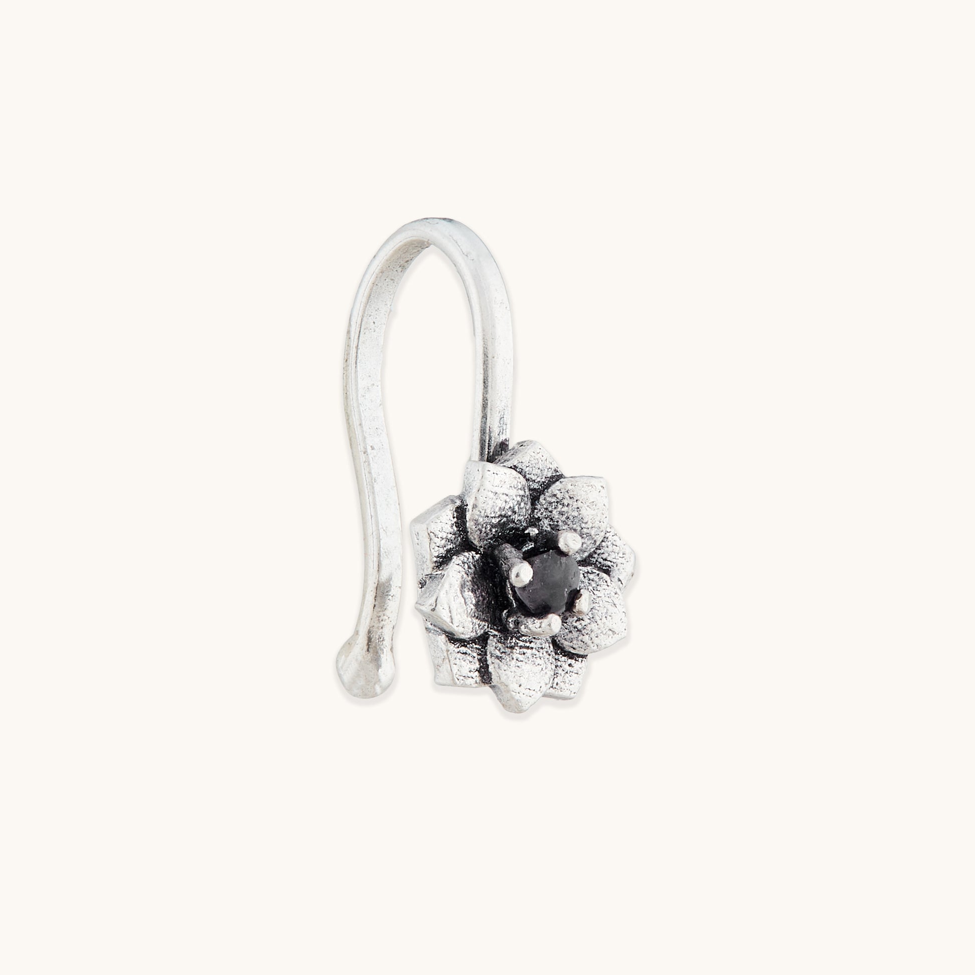 An angled view of an antique-finish silver clip-on nose accessory with an ornate, multi-petaled floral design and a dark central accent.