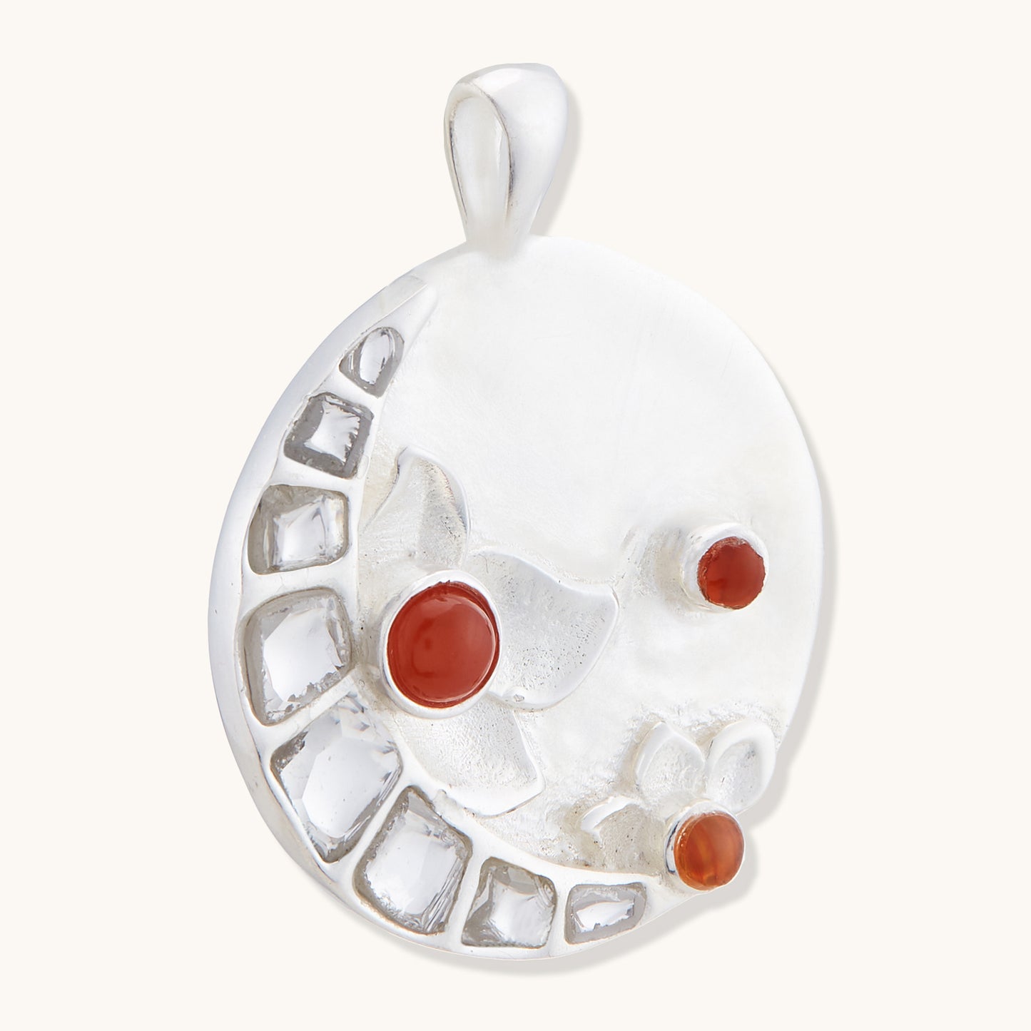 Side view of a sterling silver Full Moon pendant with set red gemstones and textured floral accents.