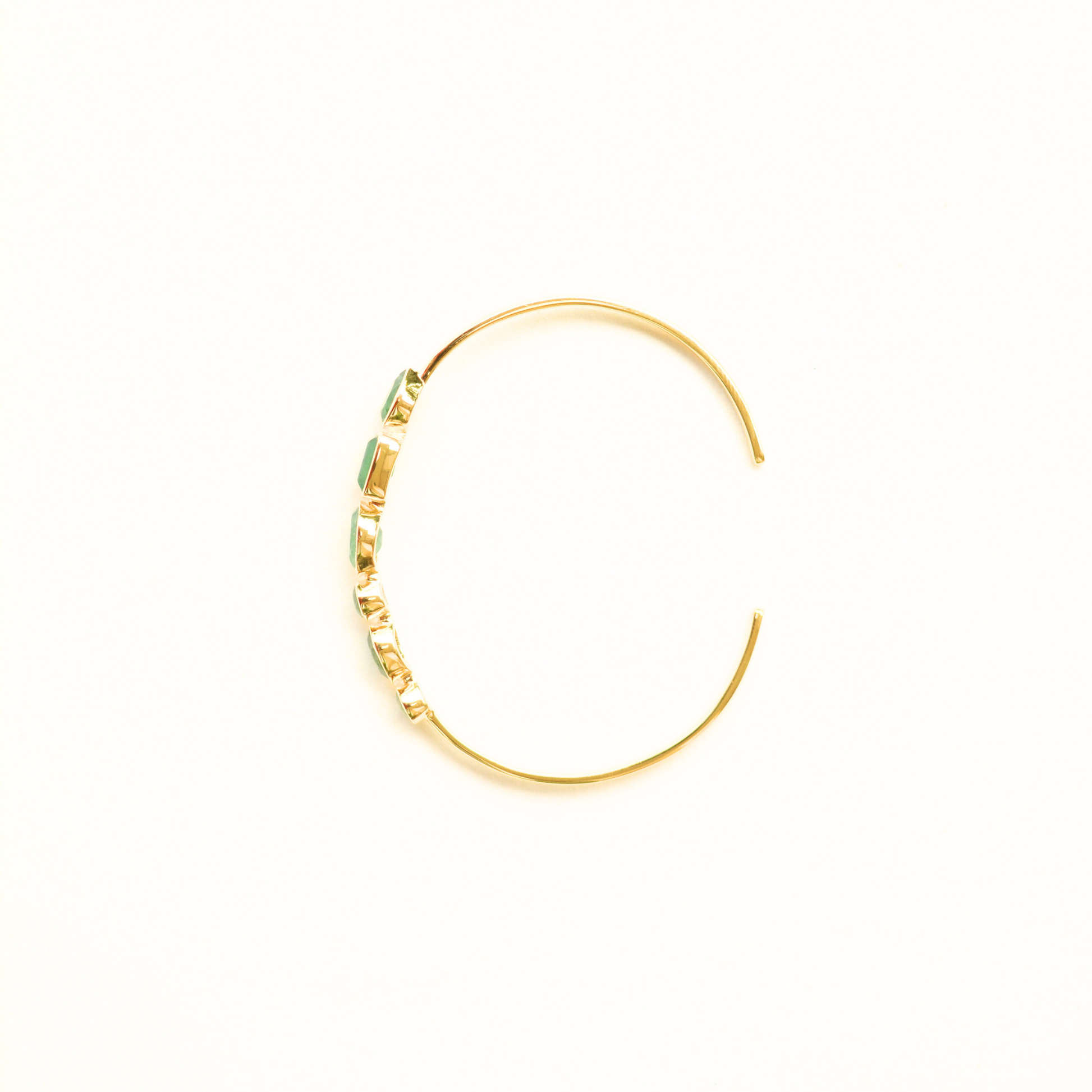 Top view of a gold-plated silver cuff bracelet highlighting the bezel-set green aventurine stones and its open-ended design.