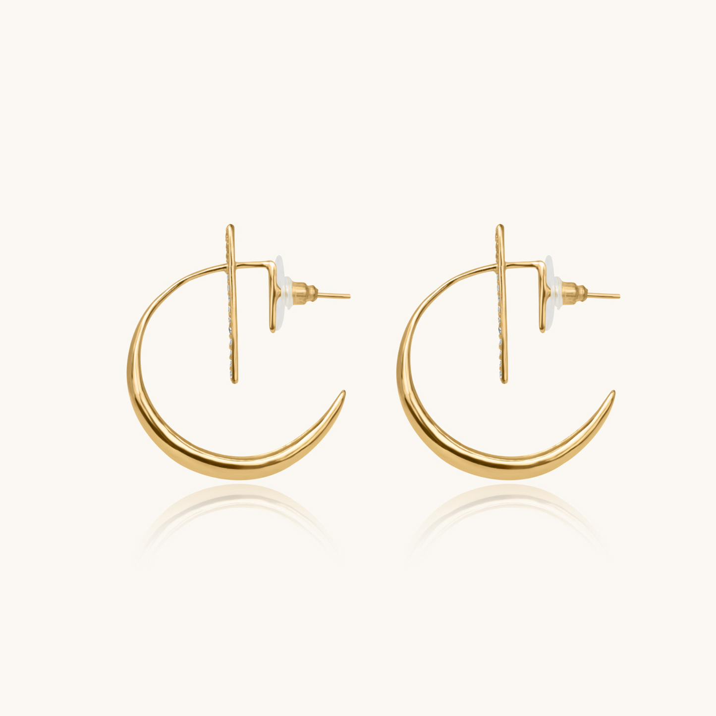 Celestial jewelry in yellow gold on a white background with a soft reflection, emphasizing the minimalist celestial jewelry design.