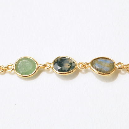 Close-up of a double-strand silver bracelet adorned with a mix of earthy, semi-precious green and grey stones, showcasing their unique natural textures.