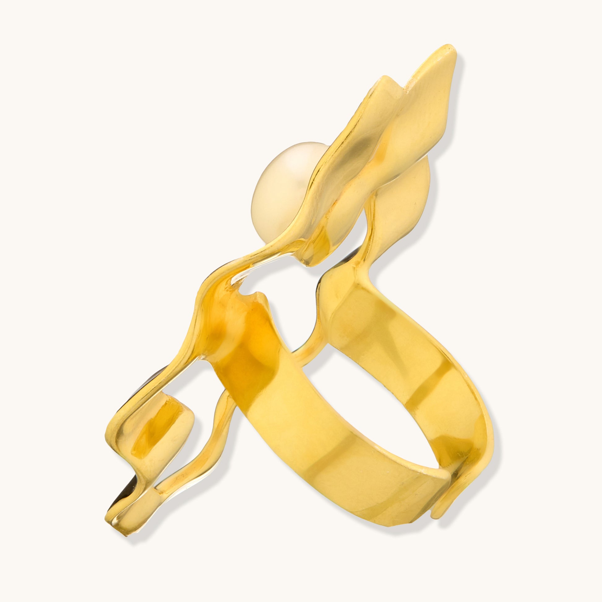 A side-angle studio shot of a gold ring with an organic, wavy structure and a pearl setting.