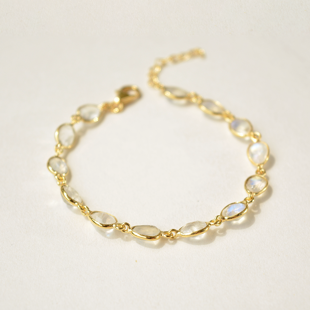 A delicate silver bracelet with a smooth, light-reflecting moonstone charm on a clean white background.