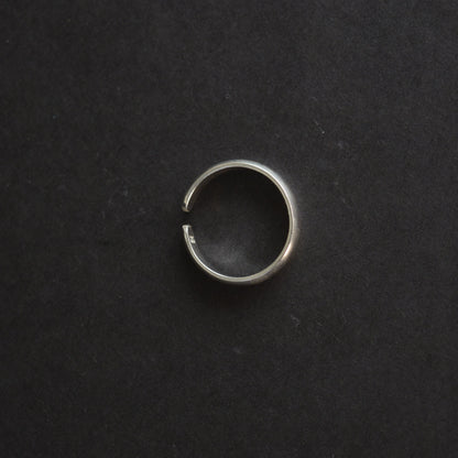 Top-down view of a polished silver band ring showing the adjustable gap and "925" hallmark stamp on a black background.