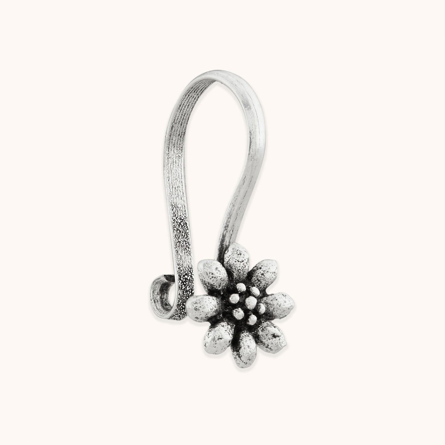 An angled close-up of a handcrafted silver nose piece, showcasing a symmetrical, multi-layered floral frame with polished metallic edges.