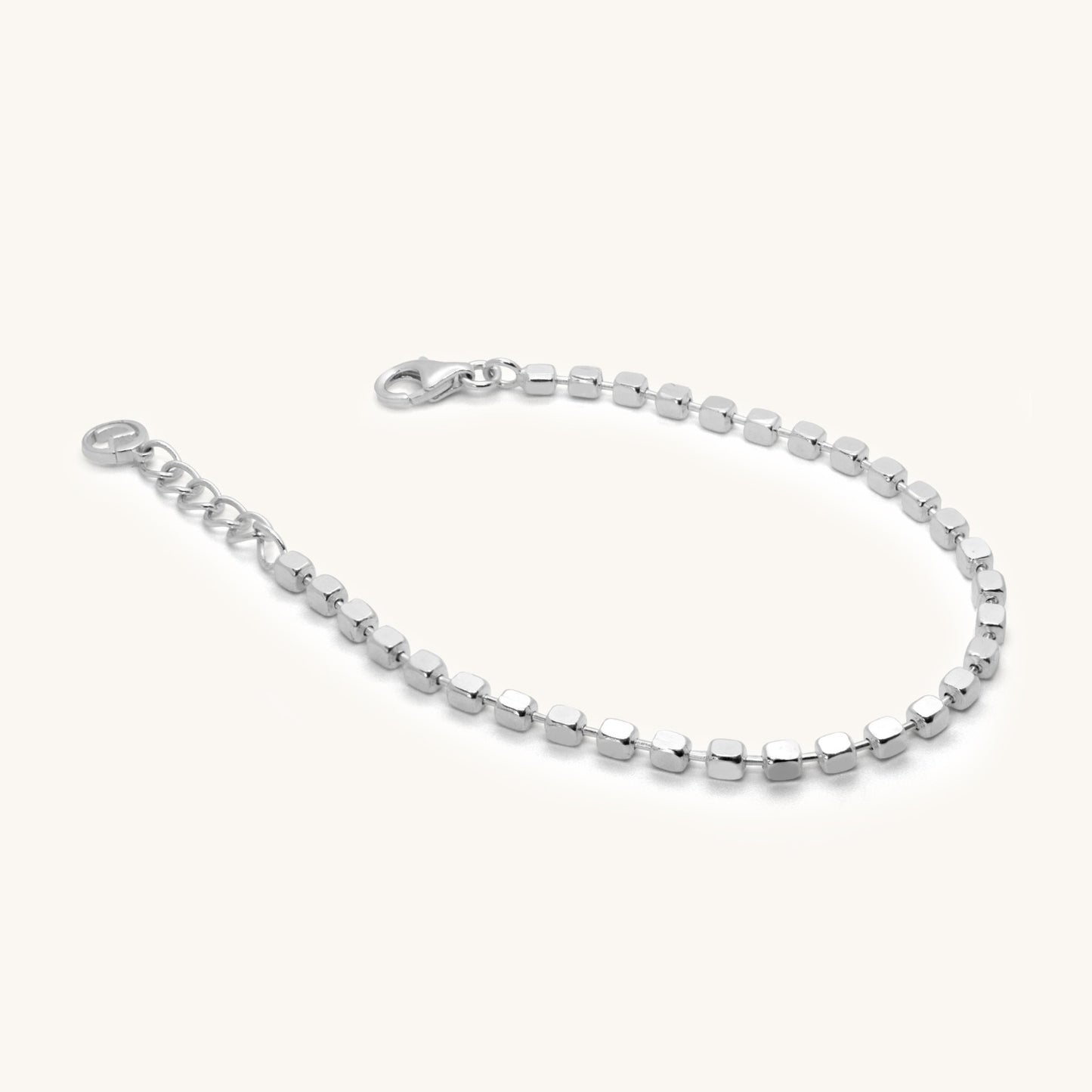 Angled view of a dainty silver bracelet with uniform square-cut beads and an adjustable extender chain for a custom fit.