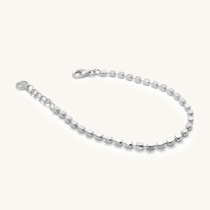 Angled view of a dainty silver bracelet with uniform square-cut beads and an adjustable extender chain for a custom fit.