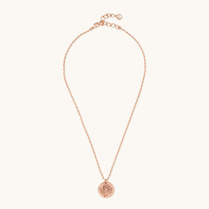 Full view of a delicate rose gold necklace with a circular sunflower medallion pendant, photographed on a white background.