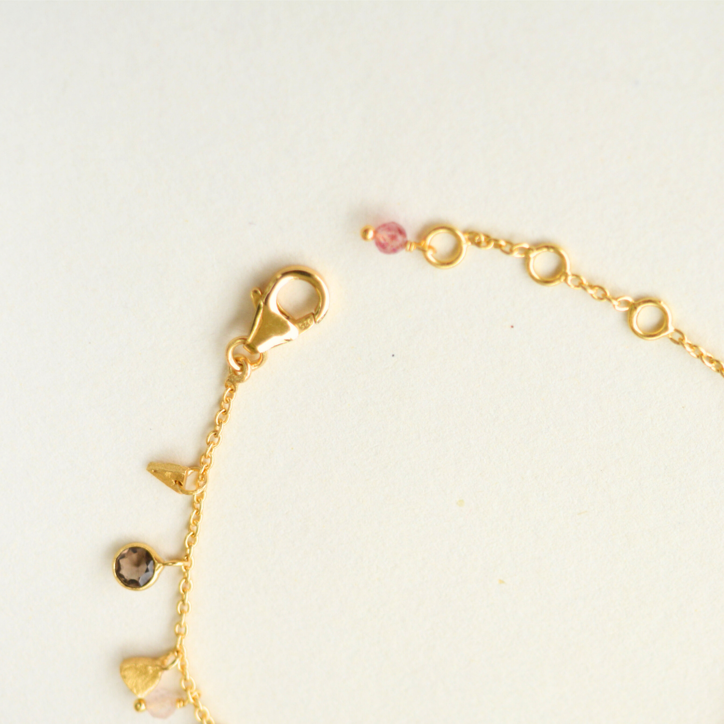 A profile view highlighting the intricate dangling charm details and the fine link structure of the gold-plated silver bracelet.