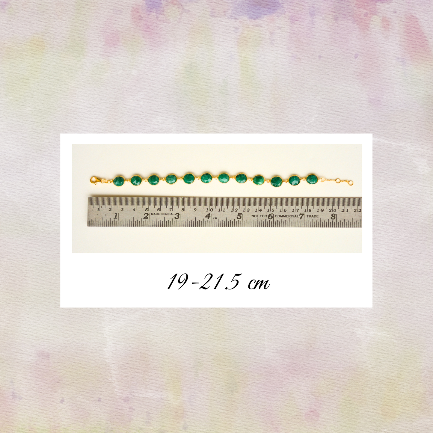 A green emerald chain bracelet displayed next to a metal ruler to show its adjustable sizing capabilities.