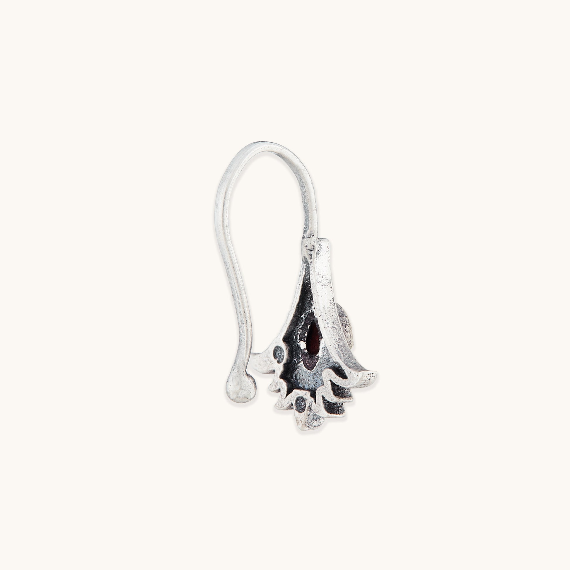 A side-profile view of a detailed silver-toned clip-on nose accessory, highlighting an ornate floral metal frame and a polished, translucent amber-hued stone.