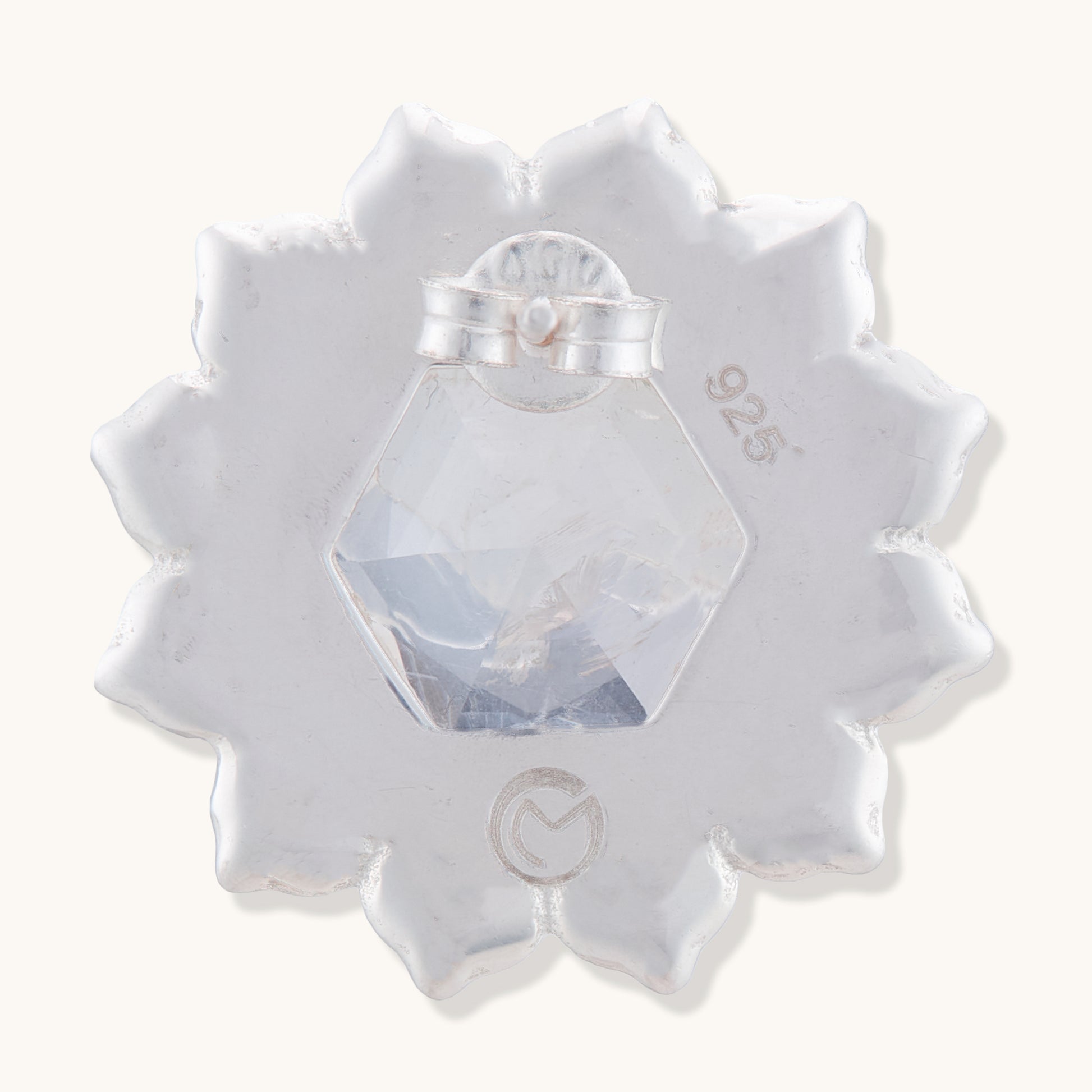 The back of a 925 sterling silver stud earring showing a clasp and a clear hexagonal gemstone set in a floral-shaped frame.