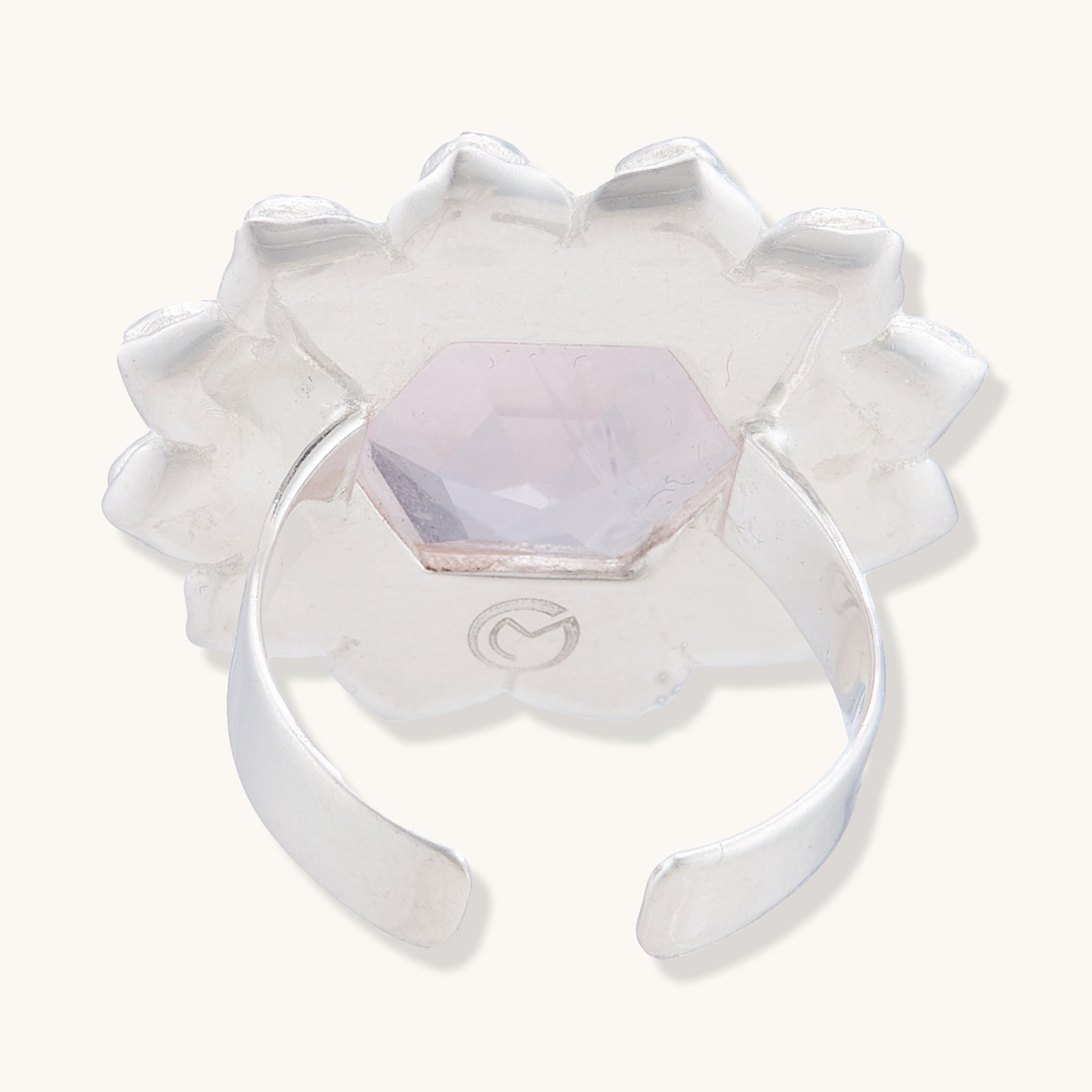 Back view of a silver adjustable ring showing the open-band design, an engraved logo, and the underside of a translucent pink hexagonal gemstone.