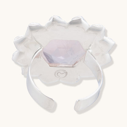 Back view of a silver adjustable ring showing the open-band design, an engraved logo, and the underside of a translucent pink hexagonal gemstone.