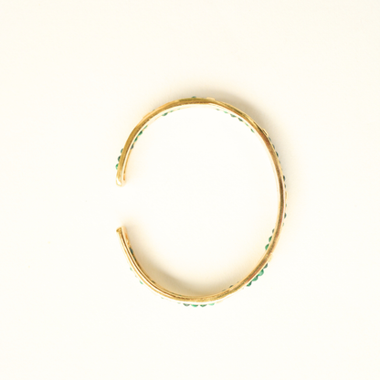 A top-down view of a circular gold-plated cuff bracelet showcasing its open-style construction.
