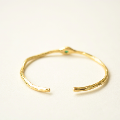A angle view of a textured gold cuff bracelet showcasing the open-style design.