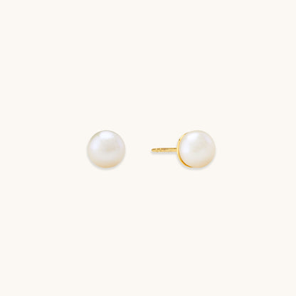 Round white freshwater pearl stud earrings set in a simple gold bezel on a white background.
