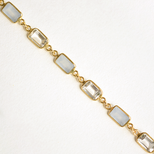 Close-up of a delicate gold-plated bracelet with polished rectangular gemstones.