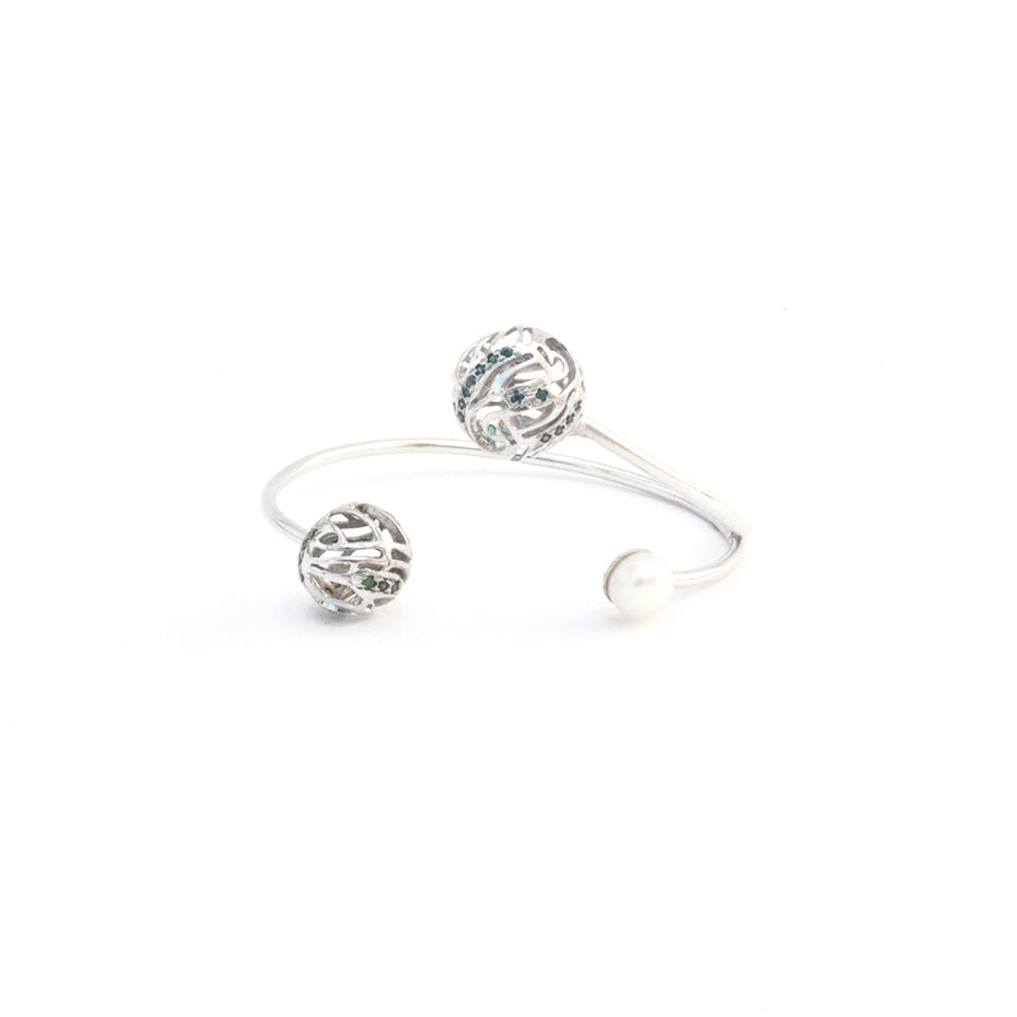 Front View of a silver open-design bracelet adorned with two intricate, hollow spherical charms and a pearl, isolated on a white background.