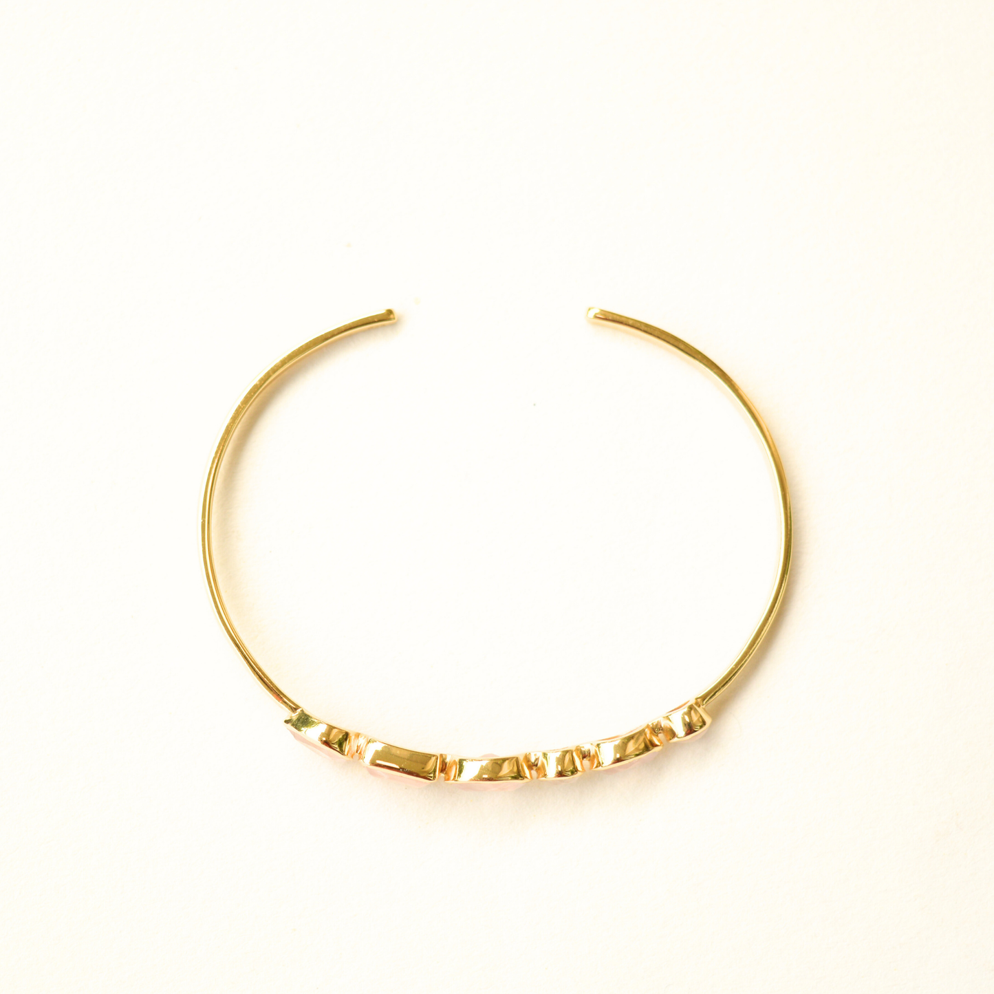 A top view of a gold-plated cuff bracelet showcasing its open-style silver metal band.
