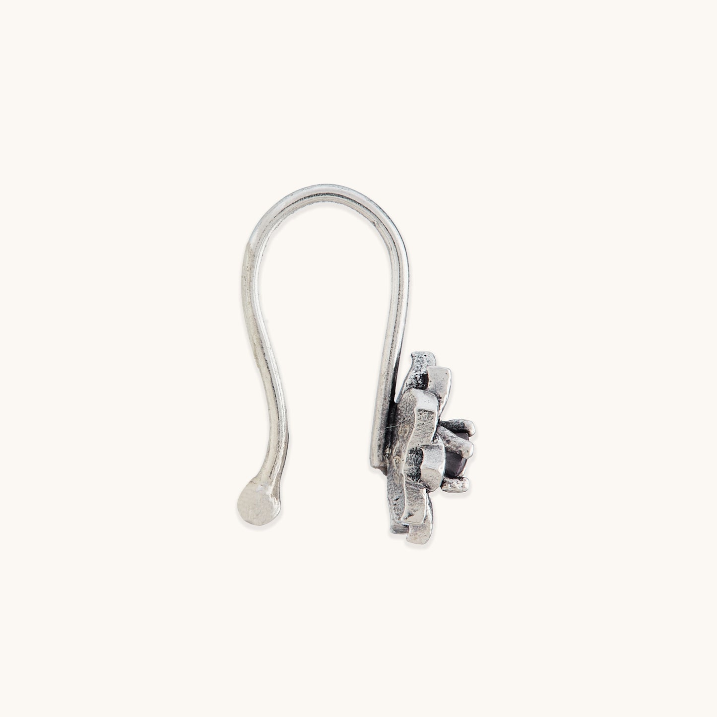A direct side view of an elegant, non-piercing silver nose ring with an ornate, petal-textured metal casing.