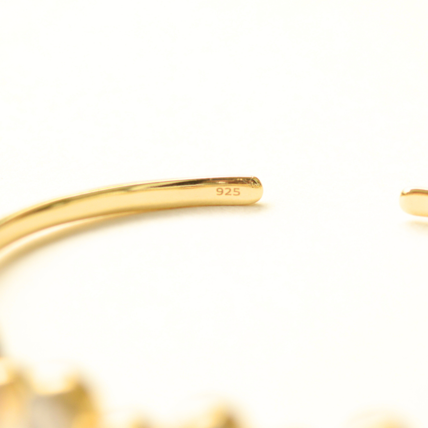 Flat-lay view of an elegant open-style silver cuff  emphasizing on the 925 purity mark.