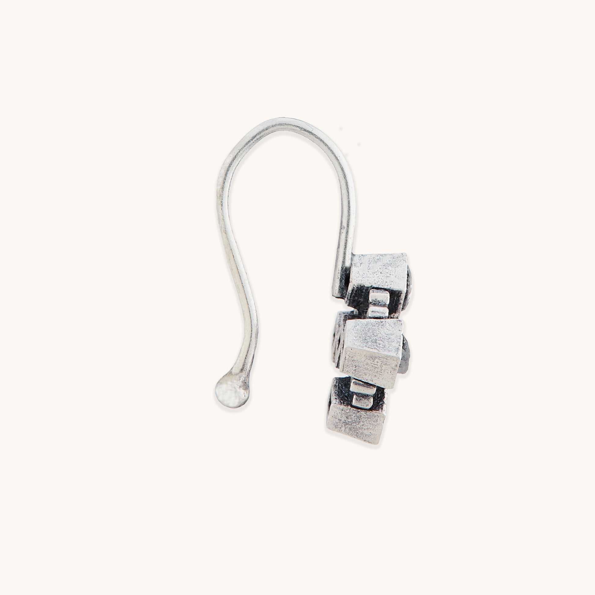 A direct side profile view of a silver-toned, geometric clip-on nose ring, focusing on the textured metallic edges.