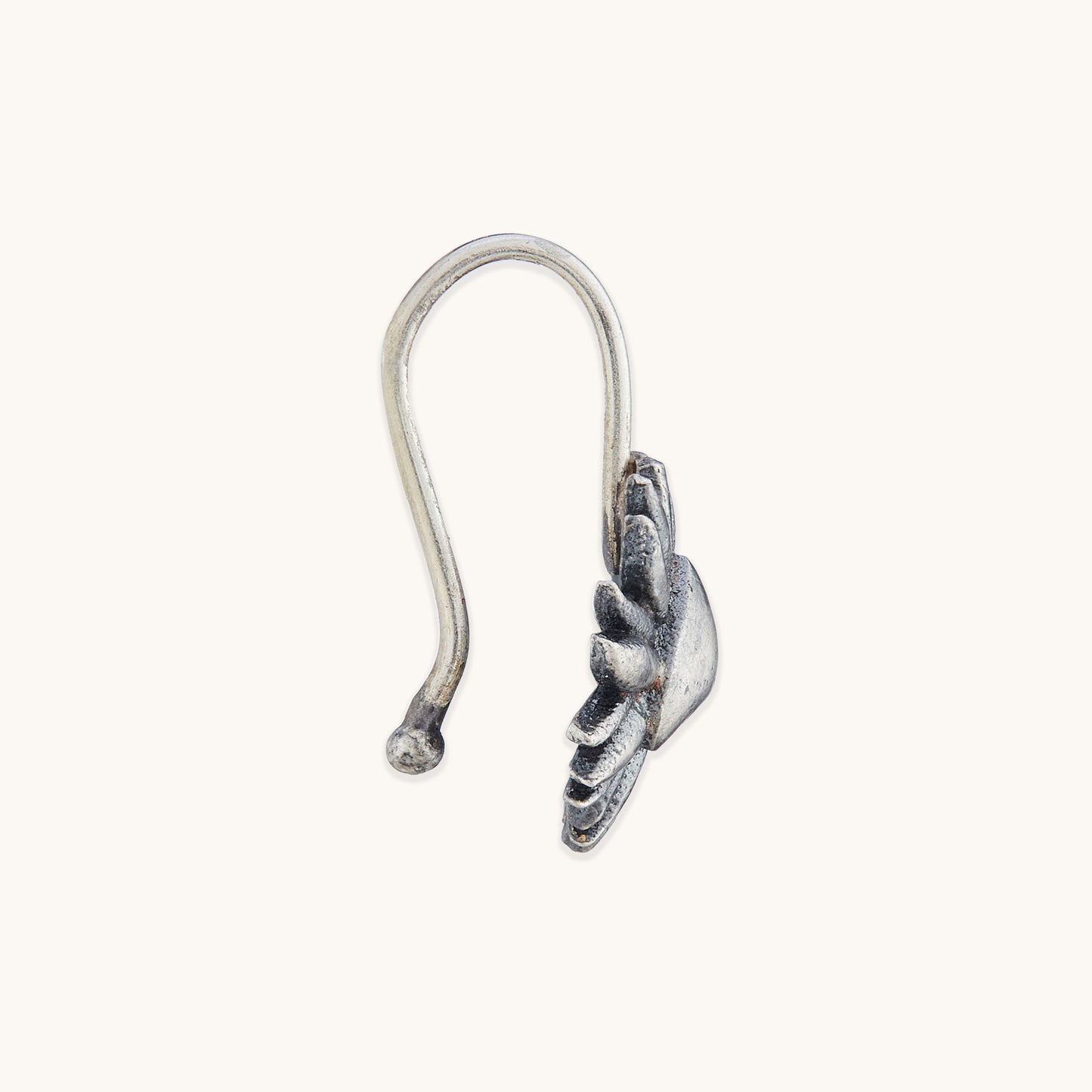 Close-up of the side profile and hook design of an ornate silver facial piece with sun-ray detailing.