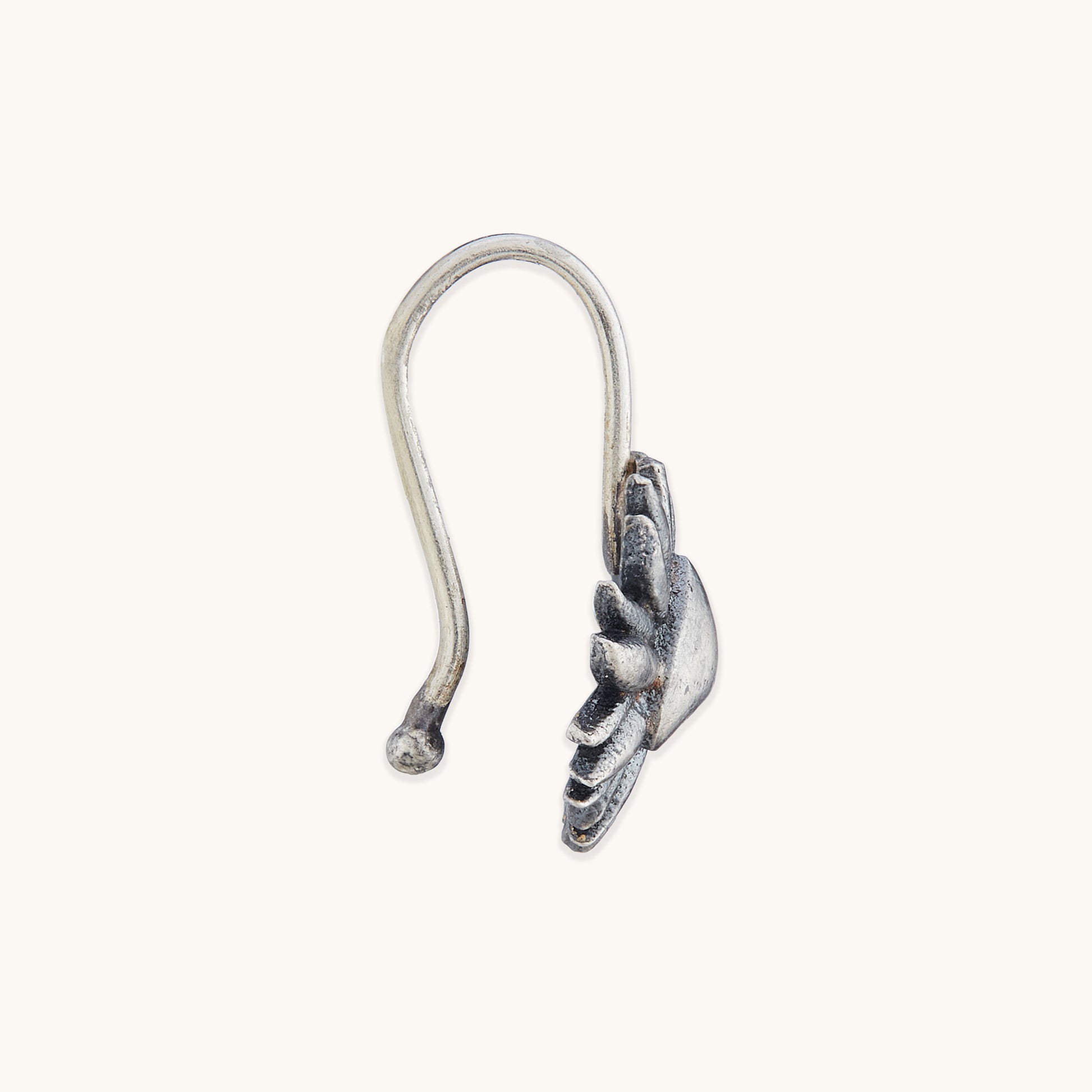 Close-up of the side profile and hook design of an ornate silver facial piece with sun-ray detailing.