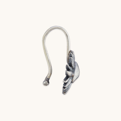 Close-up of the side profile and hook design of an ornate silver facial piece with sun-ray detailing.