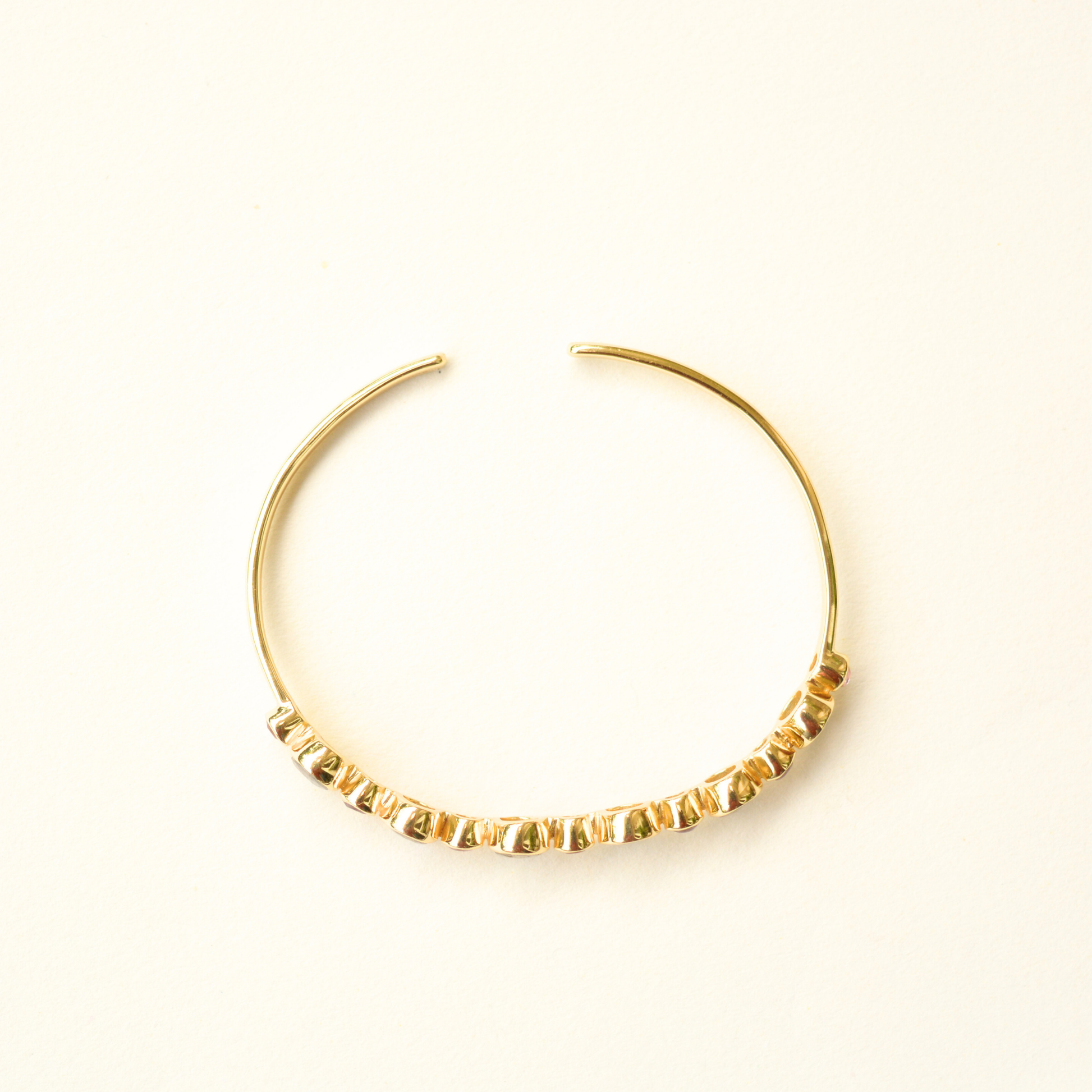 Top-view of an adjustable silver cuff bracelet showcasing the vibrant contrast between its purple and iridescent stone settings.