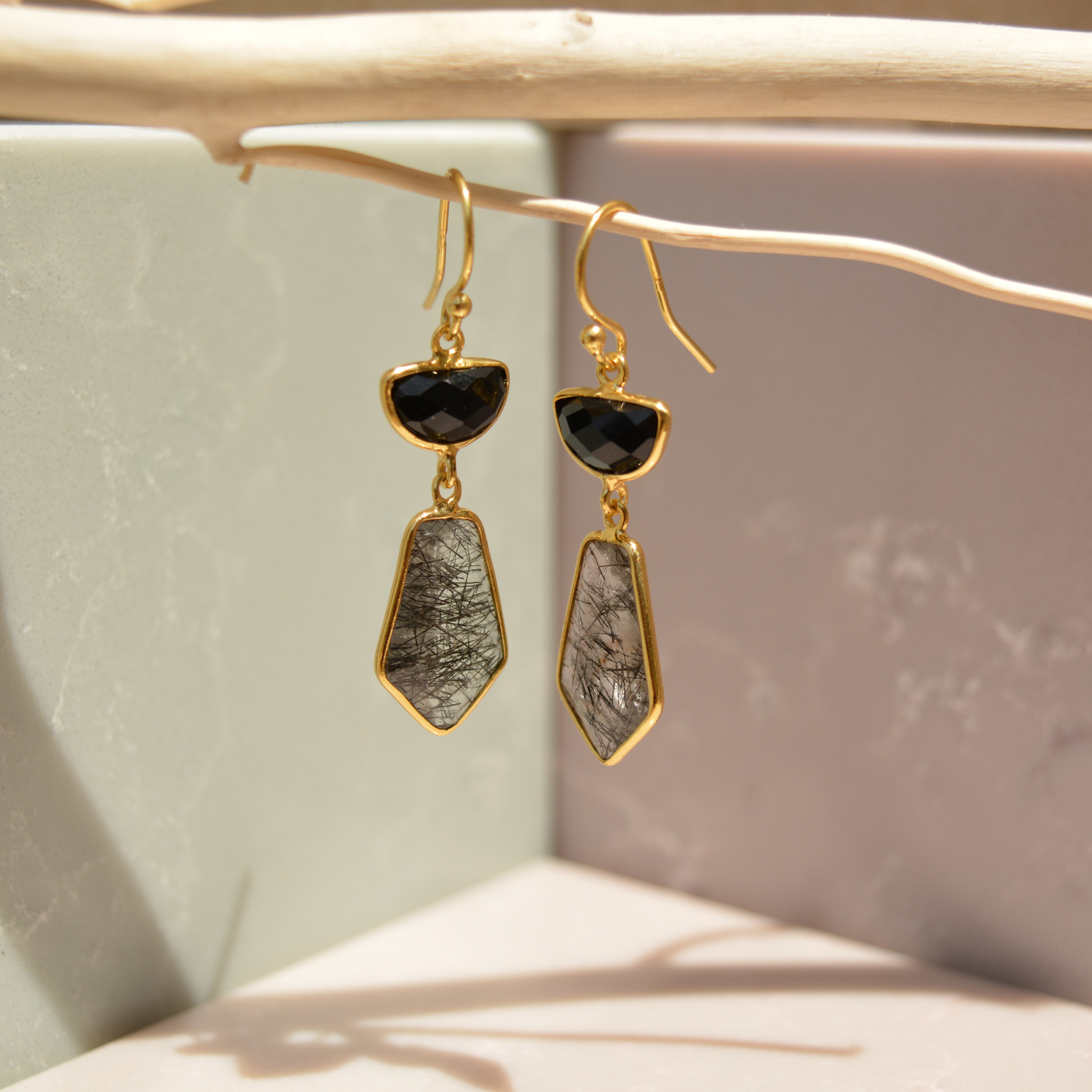 Close-up flat lay of the Midnight Strength Earrings on a white background, highlighting the unique textures of the natural black rutile stones.